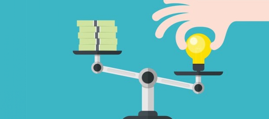 scale with a stack of money and a lightbulb